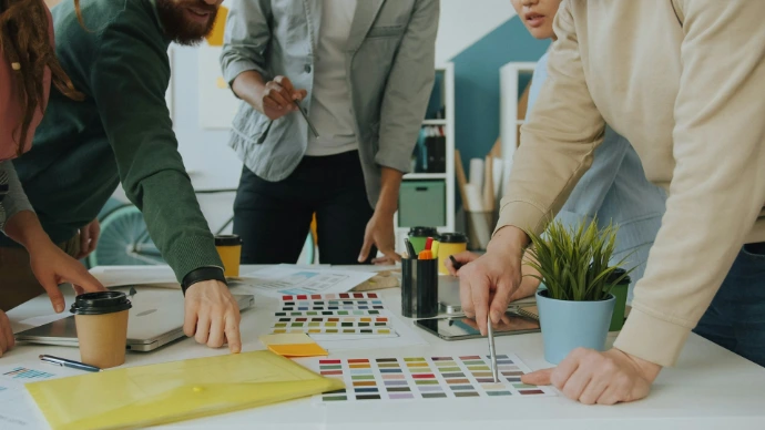 A group of people collaborating on a design project at a white table